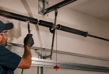 Technician working on a broken garage door torsion spring during an emergency call